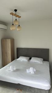a white bed with two towels on top of it at Marele Hills Boutique Apartments in Nea Fokea