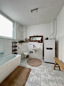 ein Badezimmer mit einer Badewanne, einem Waschbecken und einem Kühlschrank in der Unterkunft Seestern in Warnemünde