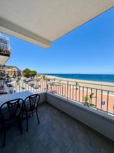 - un balcon avec une table et des chaises et la plage dans l'établissement Affacciati sulle Eolie Appartamenti sul Lungomare Patti Marina, à Patti