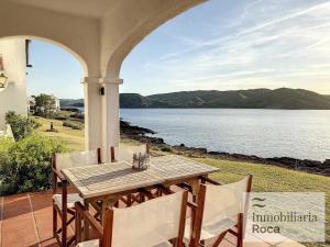 een tafel en stoelen op een veranda met uitzicht op het water bij P82. Apartamento marinero con Wifi y aire acondicionado in Fornells