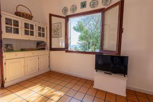 a kitchen with a flat screen tv and a window at Trilocale Maestrale Beach in Portoferraio