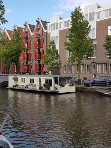a house on the side of a river with buildings at Pantheos Top Houseboat in Amsterdam