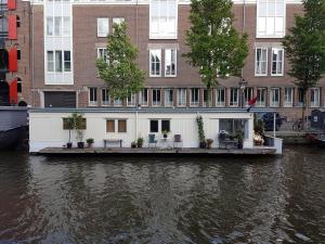 a house on a dock on a river with buildings at Pantheos Top Houseboat in Amsterdam