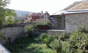 a backyard of a house with a brick wall at Ilgar's Guesthouse in Sheki