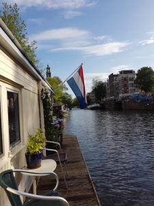 a view of a river with chairs and a flag at Pantheos Top Houseboat in Amsterdam