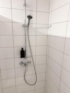 a shower with a shower head on a white tiled wall at Hôtel Ecochic, Mont-de-Marsan Sud in Saint-Pierre-du-Mont