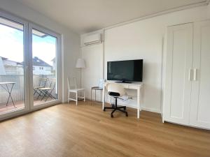 a room with a desk with a television and a table with a chair at LUX Apartments in Mörfelden-Walldorf