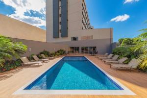 uma piscina com cadeiras e um edifício em Hotel Thomasi Express - Londrina em Londrina
