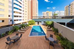 un patio de apartamentos con piscina, mesas y sillas en Hotel Thomasi Express - Londrina en Londrina