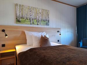 Tjeldsundbrua Hotel في Evenskjer: غرفة نوم بسرير مع لوحة على الحائط