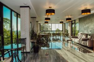 Capo Verde Hotel Batumi في باتومي: غرفة معيشة مع طاولات وكراسي ونوافذ
