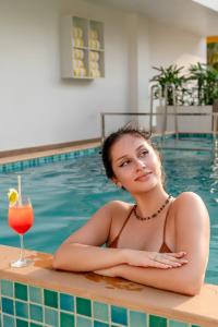 a woman in a swimming pool with a drink at Bloom Hotel - Dona Paula in Panaji