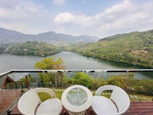 a balcony with two chairs and a view of a river at The Lake Ambience Resort in Bhīm Tāl