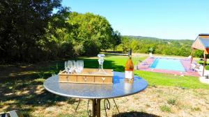 einen Tisch mit einer Flasche Wein und Gläsern darauf in der Unterkunft les gîtes de fred en Dordogne, Maisons avec piscines privées et chauffées in Florimont-Gaumiers