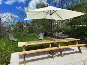 a picnic table with an umbrella and a bench at Blancs Vercors, appartement-gîte in Lans-en-Vercors