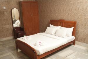 Schlafzimmer mit einem Bett mit weißer Bettwäsche und einem Spiegel in der Unterkunft Le Radha Grand in Mahabalipuram