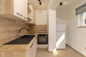 eine Küche mit weißen Schränken und einer Spüle in der Unterkunft Beachfront Apartment Betty - Happy Rentals in Vrbnik