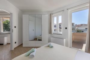 ein weißes Schlafzimmer mit einem Bett und einem großen Fenster in der Unterkunft Beachfront Apartment Betty - Happy Rentals in Vrbnik