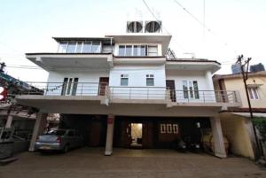a white house with a balcony on top of it at Savi's home stay in Ooty