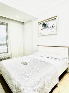 Dormitorio blanco con cama con colcha blanca en Seven hills, en Almaty