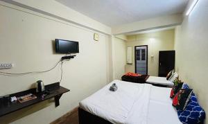 Habitación con 2 camas y TV en la pared. en FabHotel Palbhu, en Gangtok