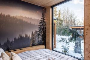 a bedroom with a large window with a winter view at ONИEA l Sauna & Spa in Petite-Rivière-Saint-François