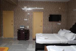 ein Hotelzimmer mit 2 Betten und einem Flachbild-TV in der Unterkunft Le Radha Grand in Mahabalipuram