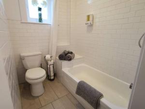 a white bathroom with a toilet and a bath tub at Old Quebec - Les Suites Montcalm #2 - Free Parking in Quebec City