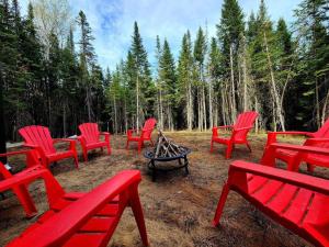 um grupo de cadeiras vermelhas sentadas à volta de uma fogueira em Le Western : Spa l Sauna l Bar l Billlard em Valcartier Station