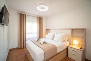 a bedroom with a large white bed with a television at Precioso Apartamento Jardin del Golf 1, Novo Sancti Petri in Chiclana de la Frontera