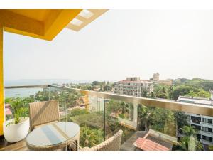 balcón con mesa, sillas y vistas al océano en Bloom Hotel - Dona Paula en Panaji