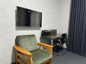 a room with a tv and a chair and a desk at Hotel Marjan in Shymkent