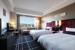 a hotel room with two beds and a flat screen tv at Hotel Nikko Kanazawa in Kanazawa