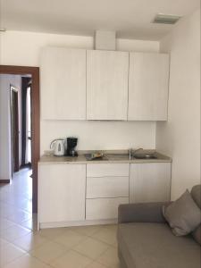 a kitchen with white cabinets and a couch in a room at Le Corti Del Lago in Padenghe sul Garda
