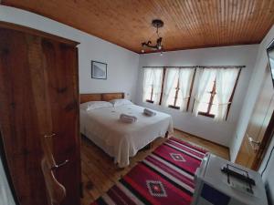 a bedroom with a bed and two windows and a rug at Guest House J.Prifti in Berat
