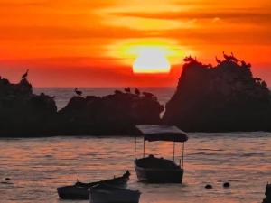 un coucher de soleil sur l'océan avec des bateaux dans l'eau dans l'établissement BAHÍA SUR HOUSE - San Bartolo, à San Bartolo