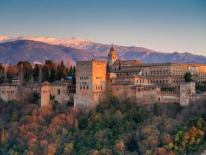 an old castle on a hill with mountains in the background at Apartamentos Realejo Campo del Príncipe 3000 in Granada