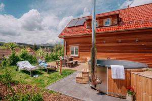 une personne assise sur une chaise à côté d'une maison avec un bain à remous dans l'établissement Das Schierke Harzresort, à Schierke