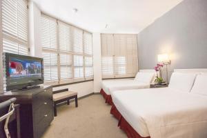 a hotel room with two beds and a flat screen tv at Grant Plaza Hotel in San Francisco