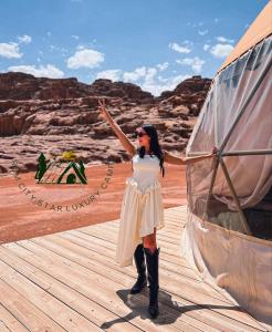 a woman in a white dress standing next to a tent at Rum city Star LUXURY Camp in Wadi Rum