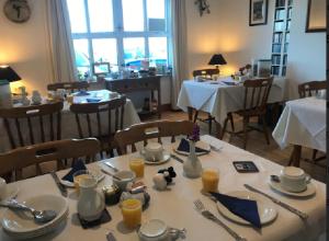 a dining room with a table with plates and utensils at Errisbeg Lodge Bed + Breakfast in Roundstone