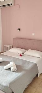 two beds with white sheets and a red rose on them at River Studios in Paleokastritsa