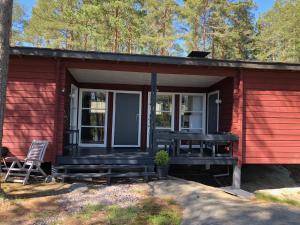 a red house with a porch and a chair in front at Stuga Pörsvik in Nauvo
