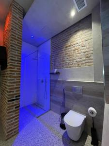 baño con aseo y ducha con luces azules en Meri Boutique Hotel en Korçë