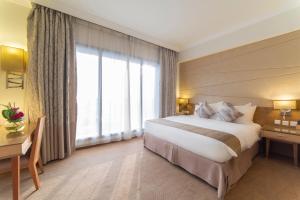 um quarto de hotel com uma cama e uma grande janela em Golden Tulip Dammam Corniche Hotel em Dammam