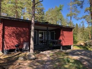 a red cabin in the woods with a tree at Stuga Pörsvik in Nauvo
