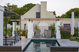 une terrasse avec des chaises et une piscine en face d'une maison dans l'établissement Macaron Boutique Guest House, à Franschhoek