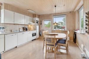 Classic Summer House 200 Meters From The Water, في Børkop: مطبخ مع دواليب بيضاء وطاولة وكراسي