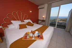 a hotel room with a bed with a tray of food at Hôtel Bellevue Cap d'Agde in Cap d'Agde