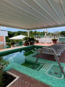 a swimming pool with chairs and a large umbrella at Resort Terme La Pergola in Casamicciola Terme +72 photos